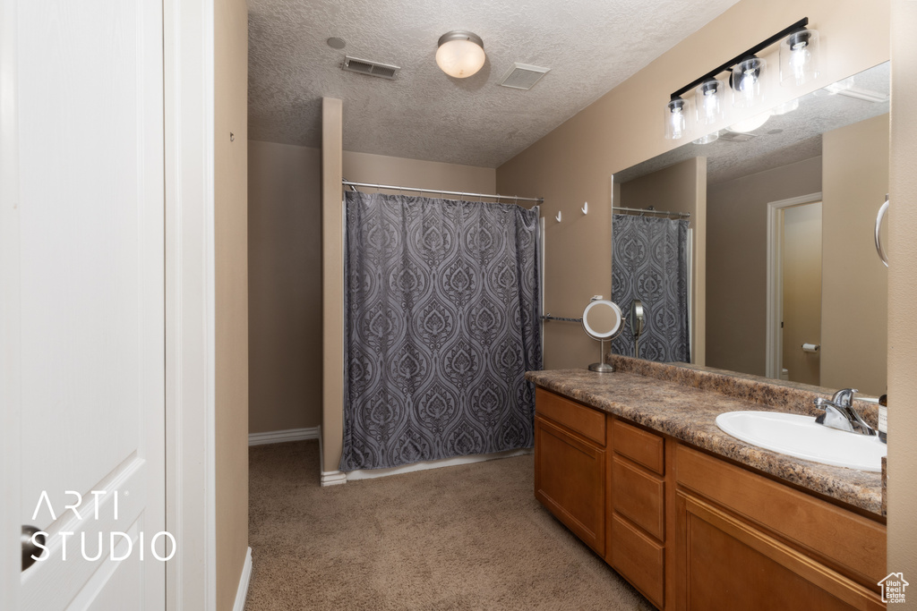 Bathroom featuring vanity, a textured ceiling, and baseboards