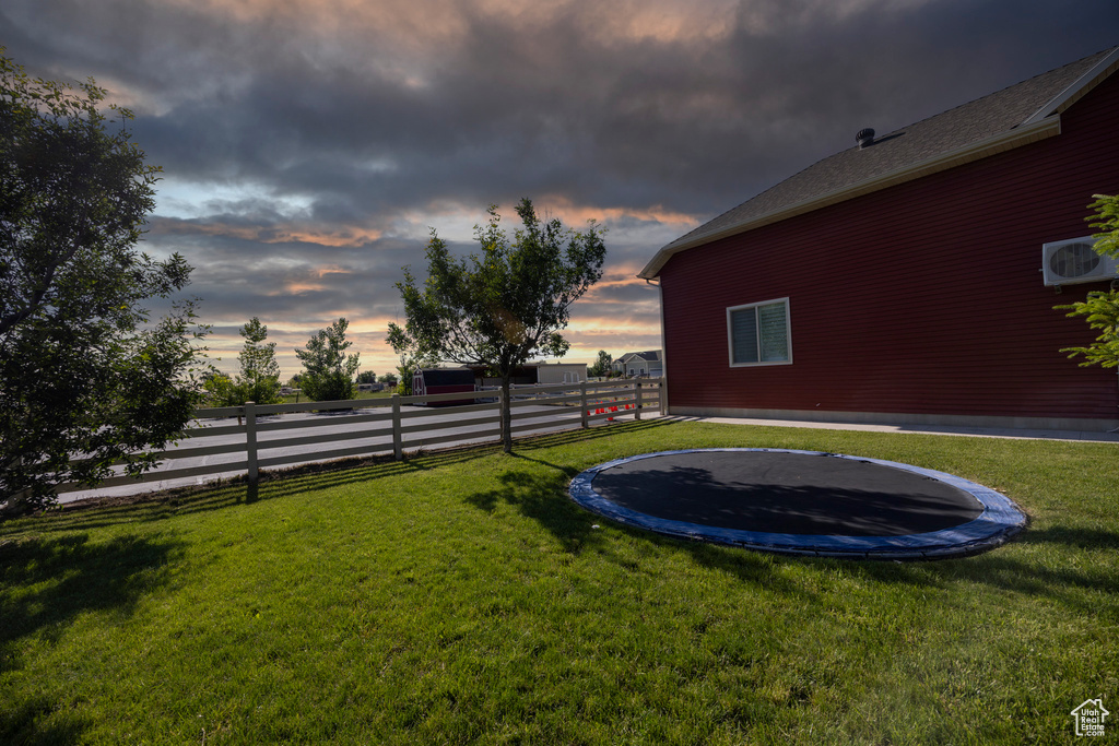 Yard at dusk featuring a trampoline