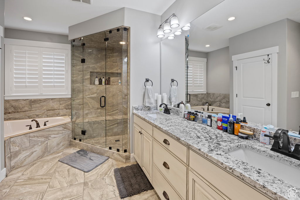 Full bathroom with double vanity, a bath, a stall shower, marble finish flooring, and recessed lighting