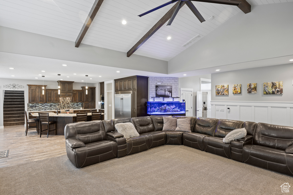 Living area with recessed lighting, ceiling fan, high vaulted ceiling, light carpet, and wood ceiling with exposed beams