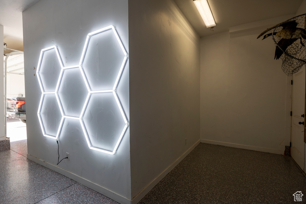 Hallway featuring speckled floor and baseboards