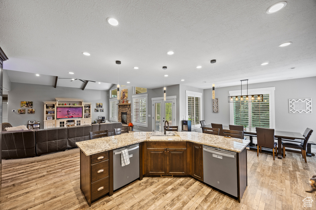 Kitchen with dishwasher, a sink, open floor plan, light wood-style floors, and recessed lighting