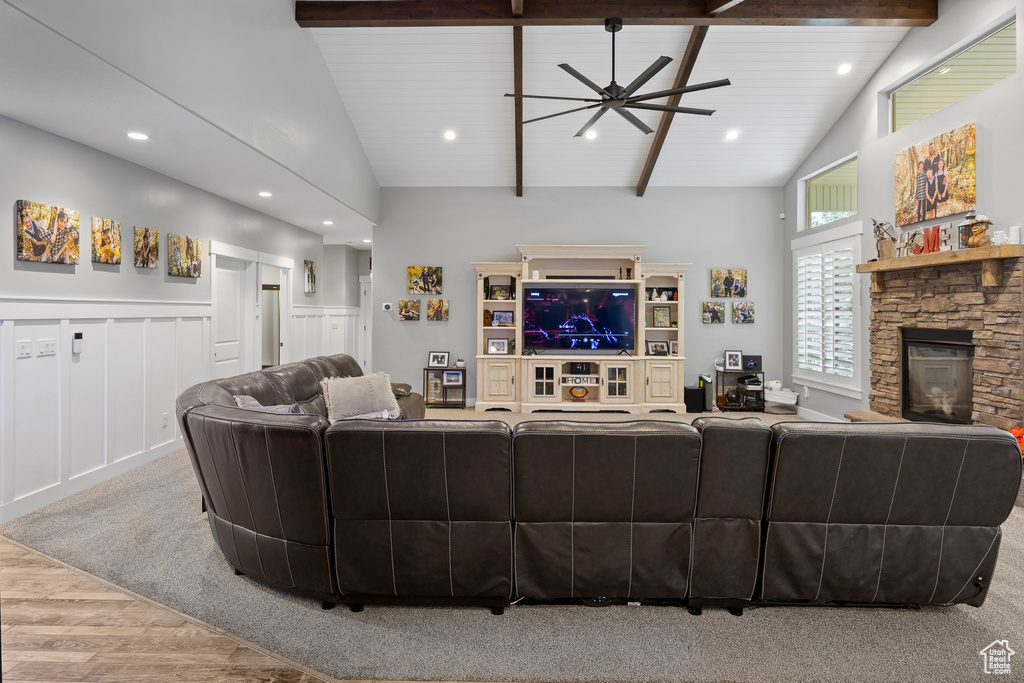 Living area featuring wood finished floors, a stone fireplace, a ceiling fan, beam ceiling, and recessed lighting