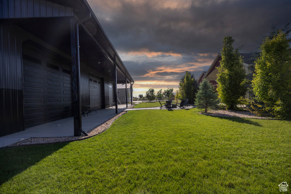 View of grassy yard with a garage and a patio area