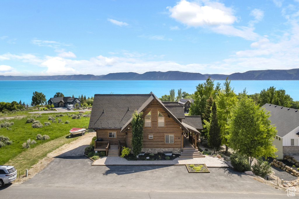 View of front of house with a water and mountain view and roof with shingles