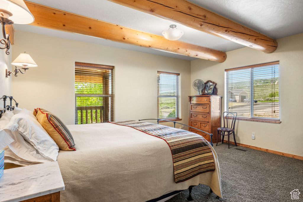 Carpeted bedroom with beam ceiling and baseboards