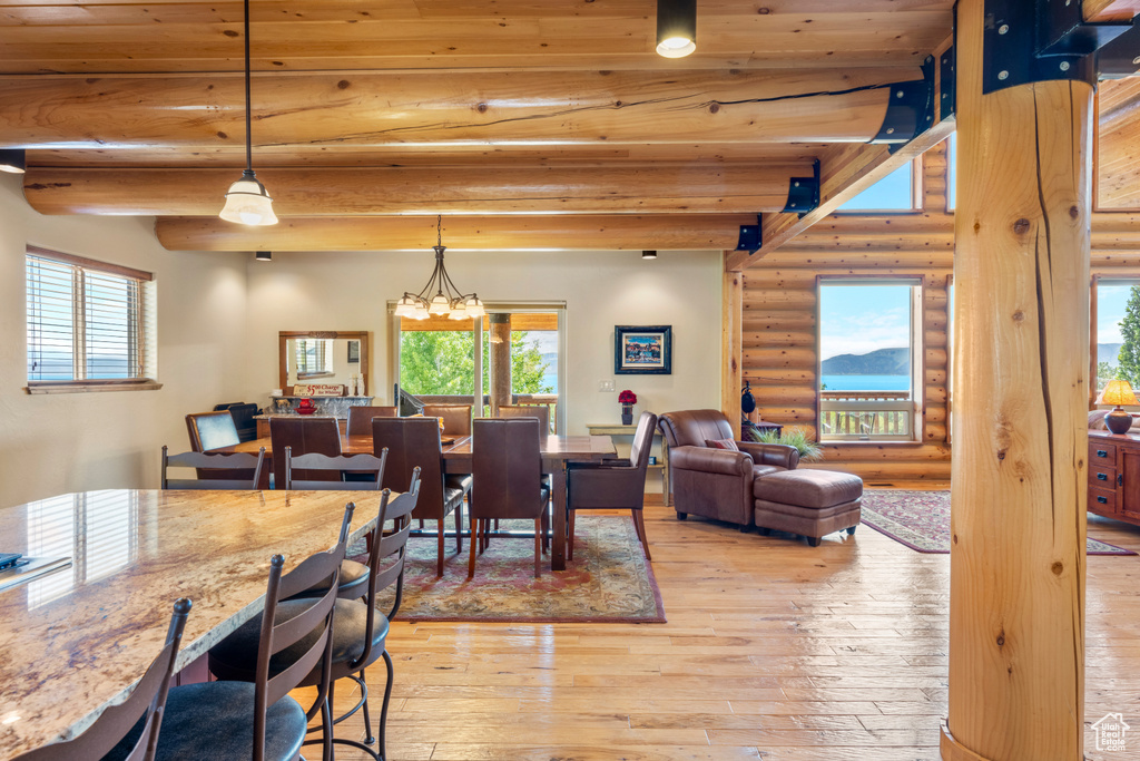 Dining space featuring rustic walls, light wood-style flooring, and beamed ceiling