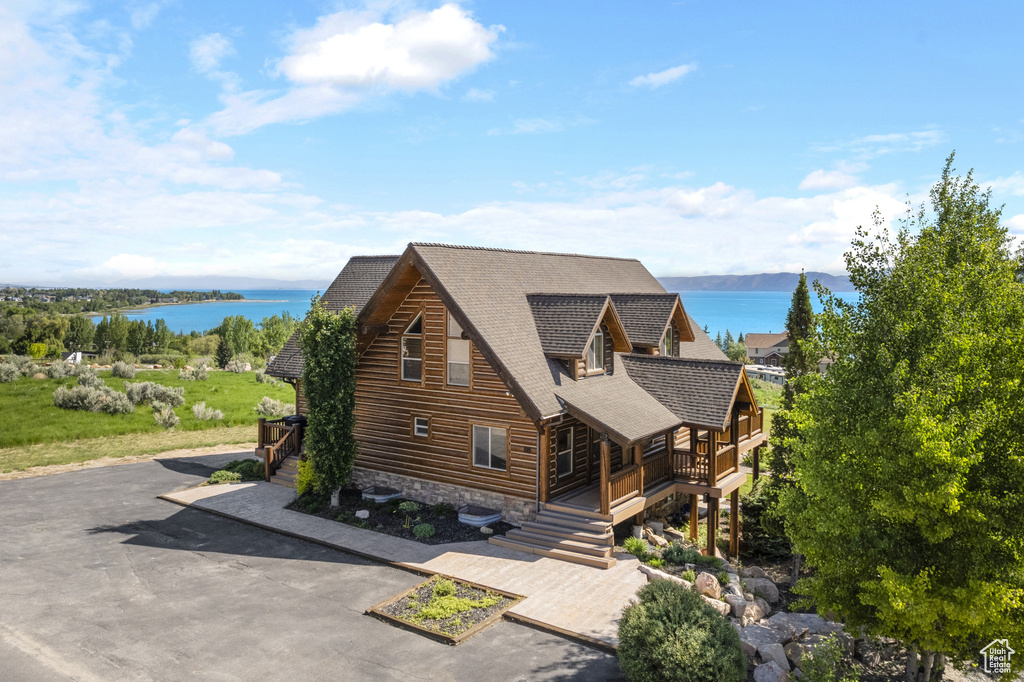 View of front of property featuring a shingled roof, a water view, and stairs