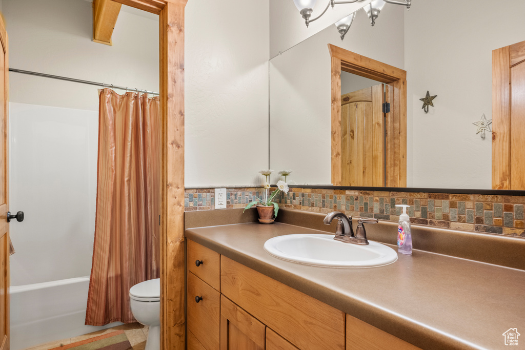 Full bath featuring toilet, vanity, shower / tub combo, and tasteful backsplash