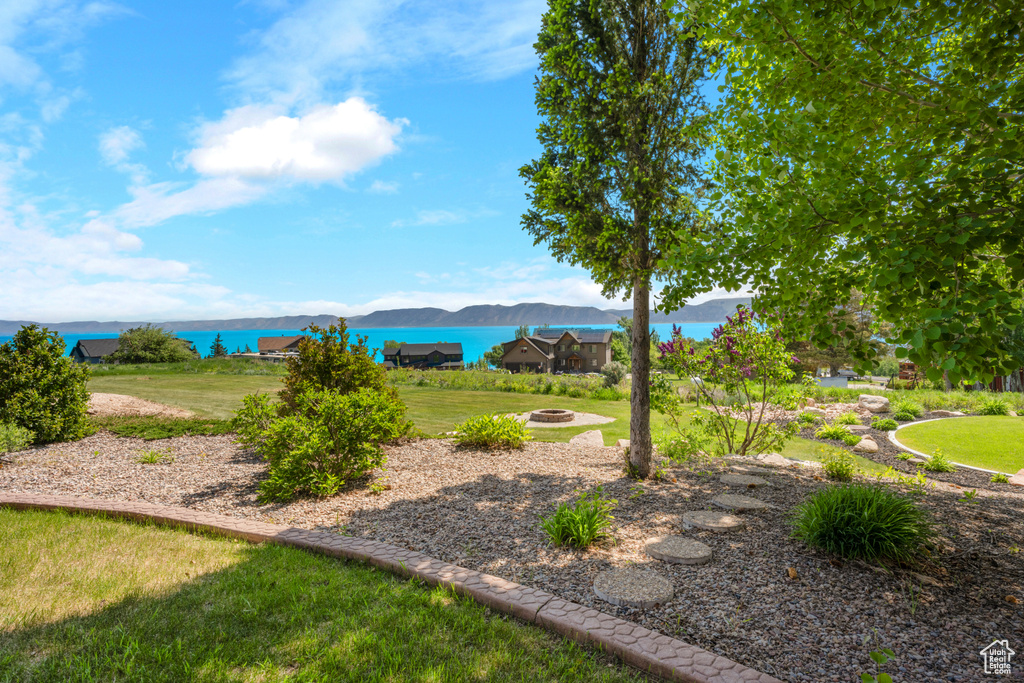 View of grassy yard with a fire pit and a water and mountain view
