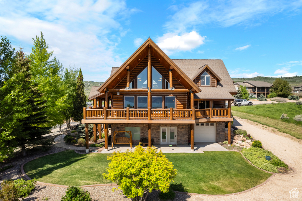 Back of property featuring stone siding, log exterior, a lawn, and a wooden deck