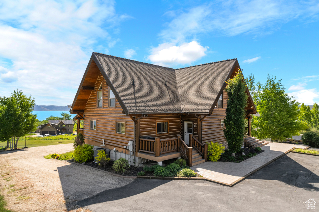 View of side of property featuring log exterior, a mountain view, and roof with shingles