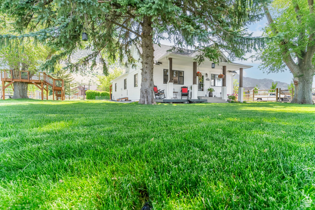 Back of house with a porch, a yard, and a mountain view