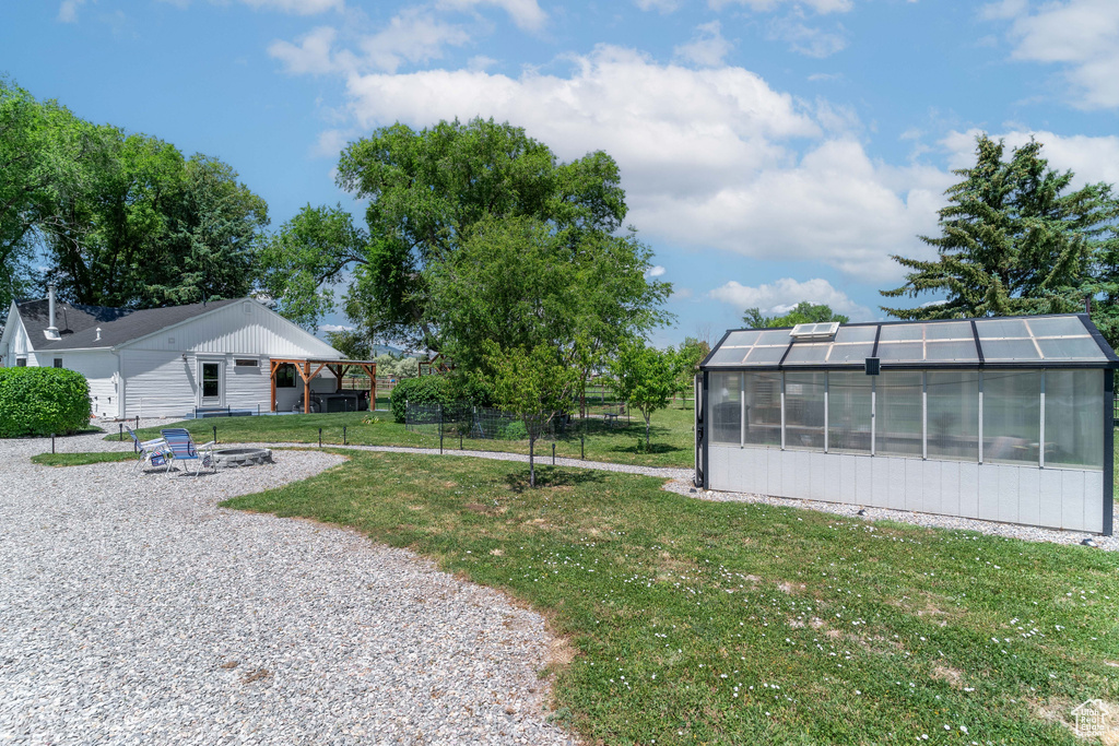 View of yard featuring a greenhouse, a fire pit, and an outdoor structure