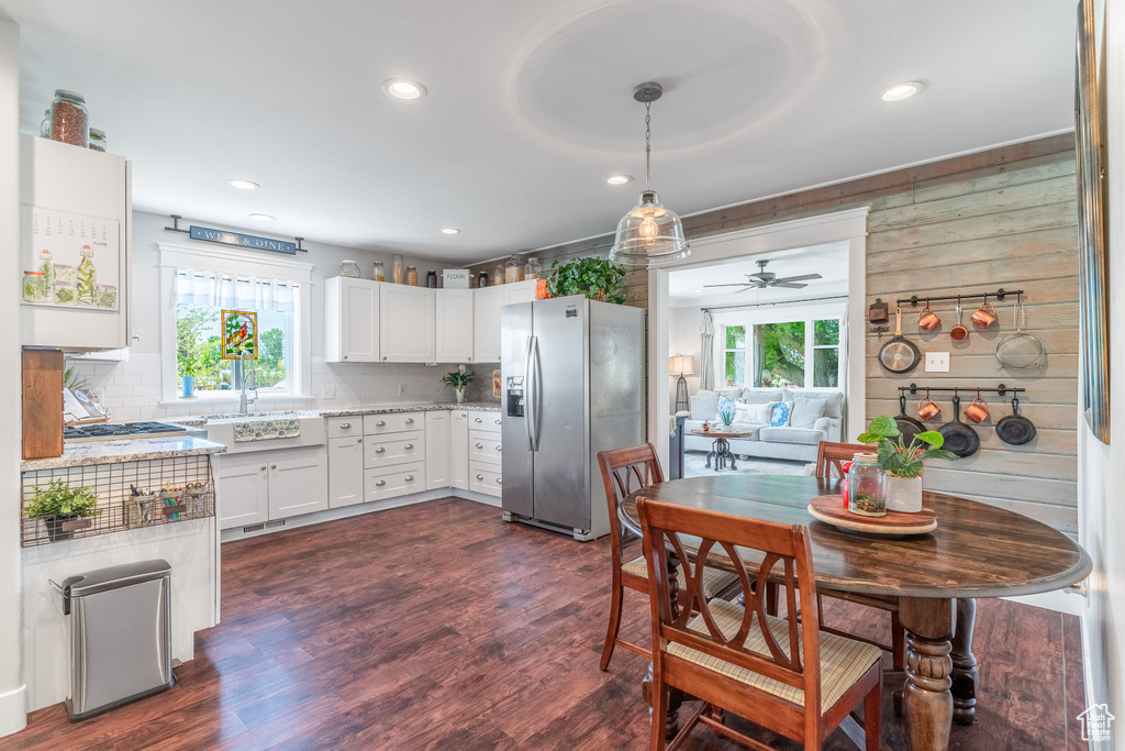 Kitchen featuring stainless steel fridge with ice dispenser, white cabinetry, ceiling fan, light stone countertops, and tasteful backsplash
