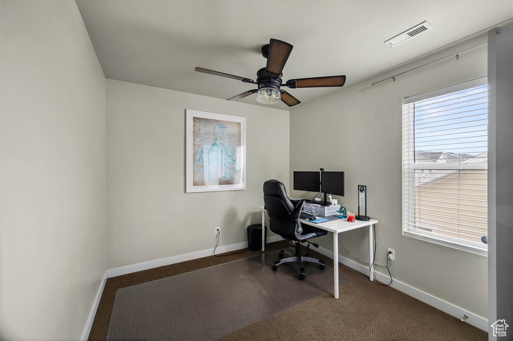 Carpeted office with baseboards and a ceiling fan