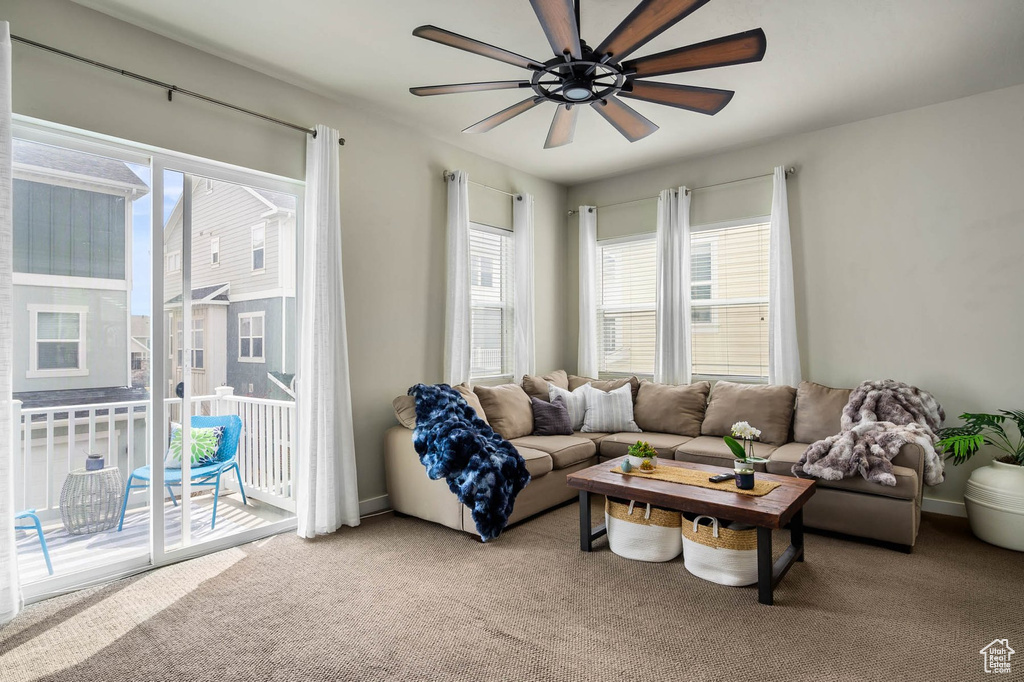 Living area featuring plenty of natural light, light colored carpet, and ceiling fan