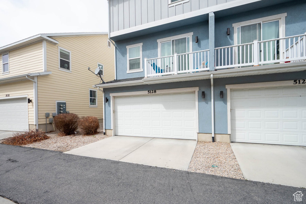View of front of house with a garage, a balcony, board and batten siding, and stucco siding