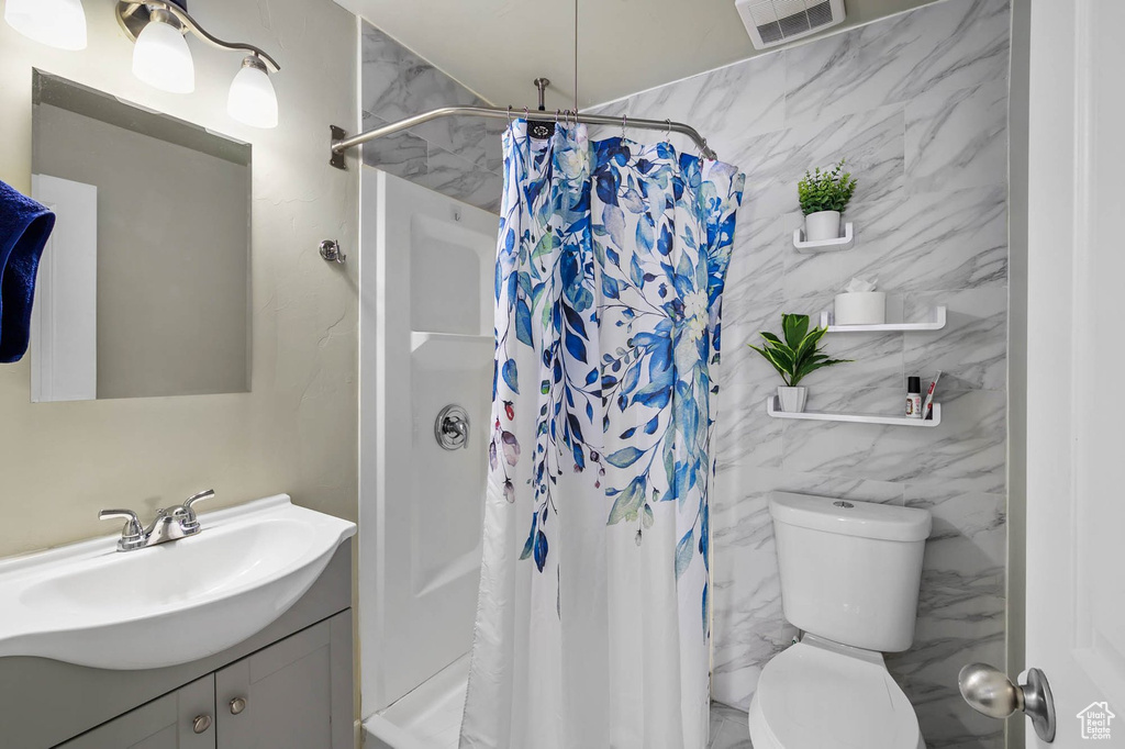 Bathroom with vanity, toilet, curtained shower, and tile walls