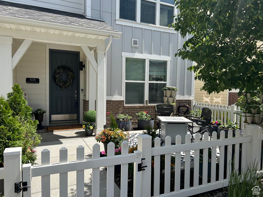 Property entrance with board and batten siding, brick siding, a gate, and covered porch
