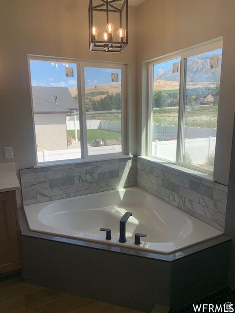 Full bathroom with a garden tub, vanity, and a chandelier