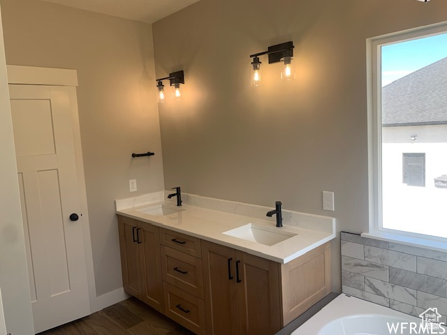 Full bath featuring a bath, wood finished floors, and double vanity