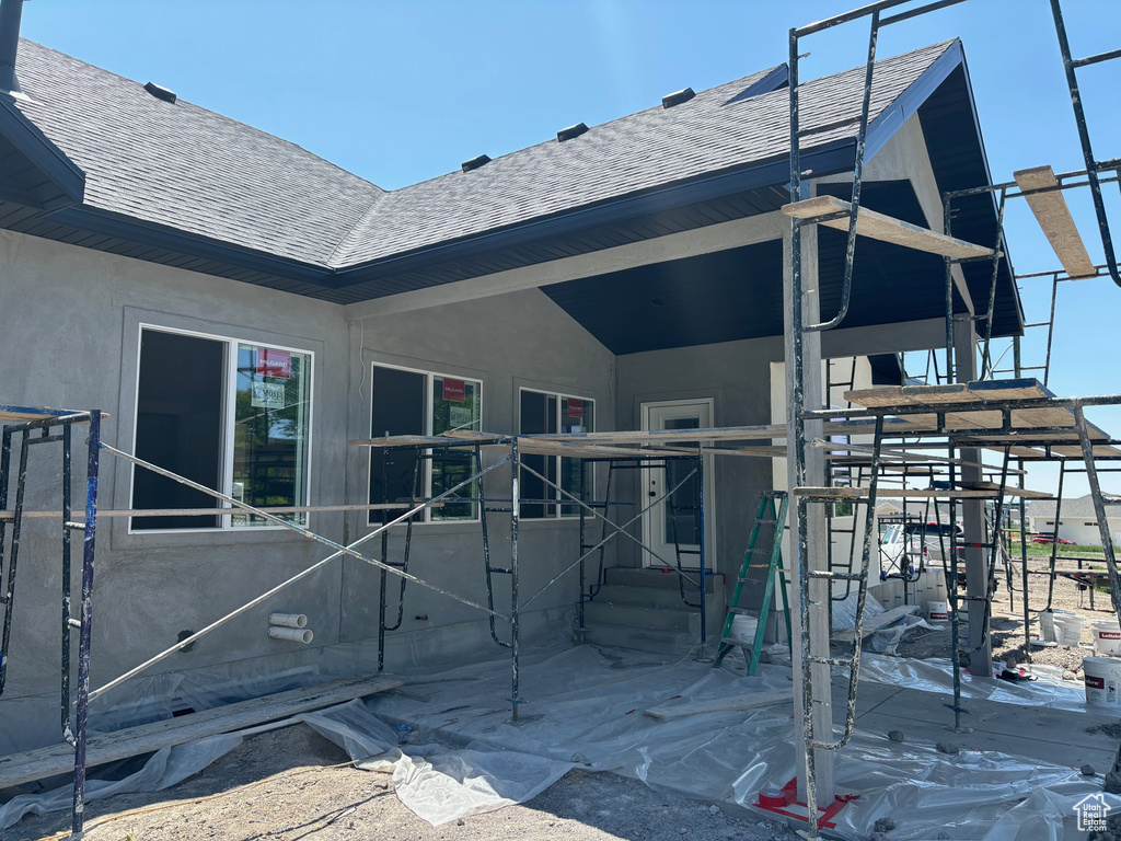 Entrance to property featuring roof with shingles and stucco siding