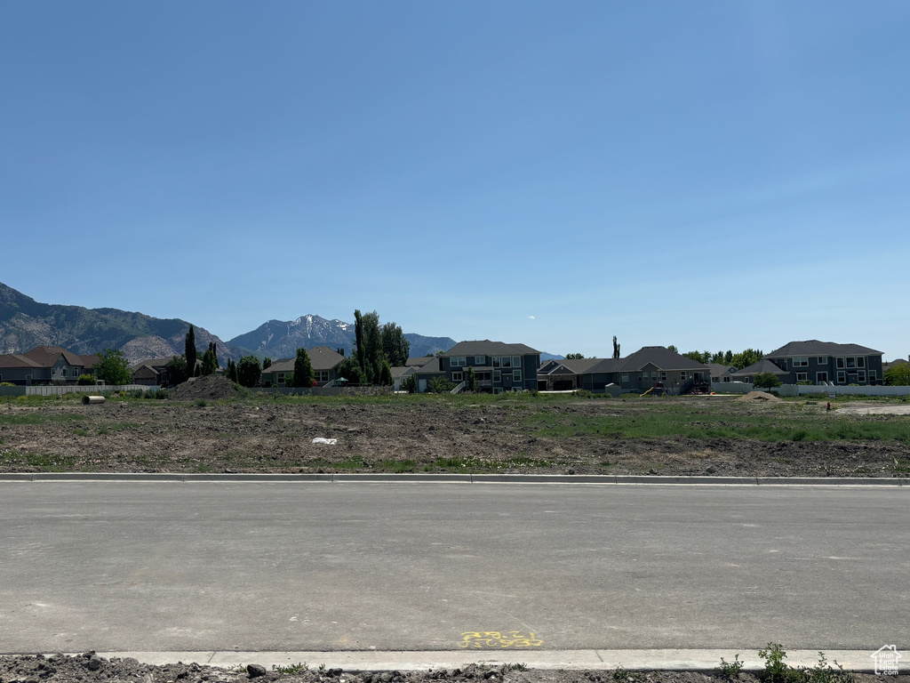 View of asphalt street featuring a mountain view, curbs, and a residential view