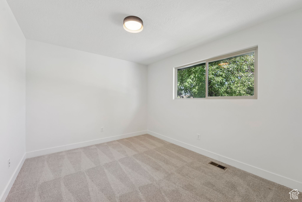 Carpeted spare room featuring baseboards