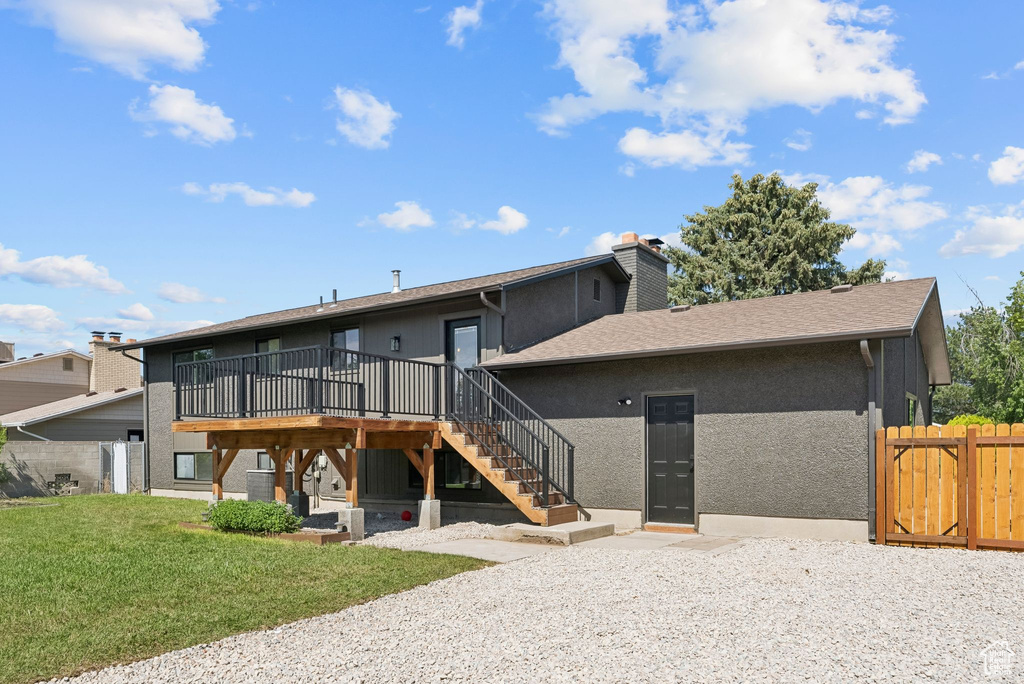 Back of property featuring stairway, a deck, a chimney, a gate, and roof with shingles