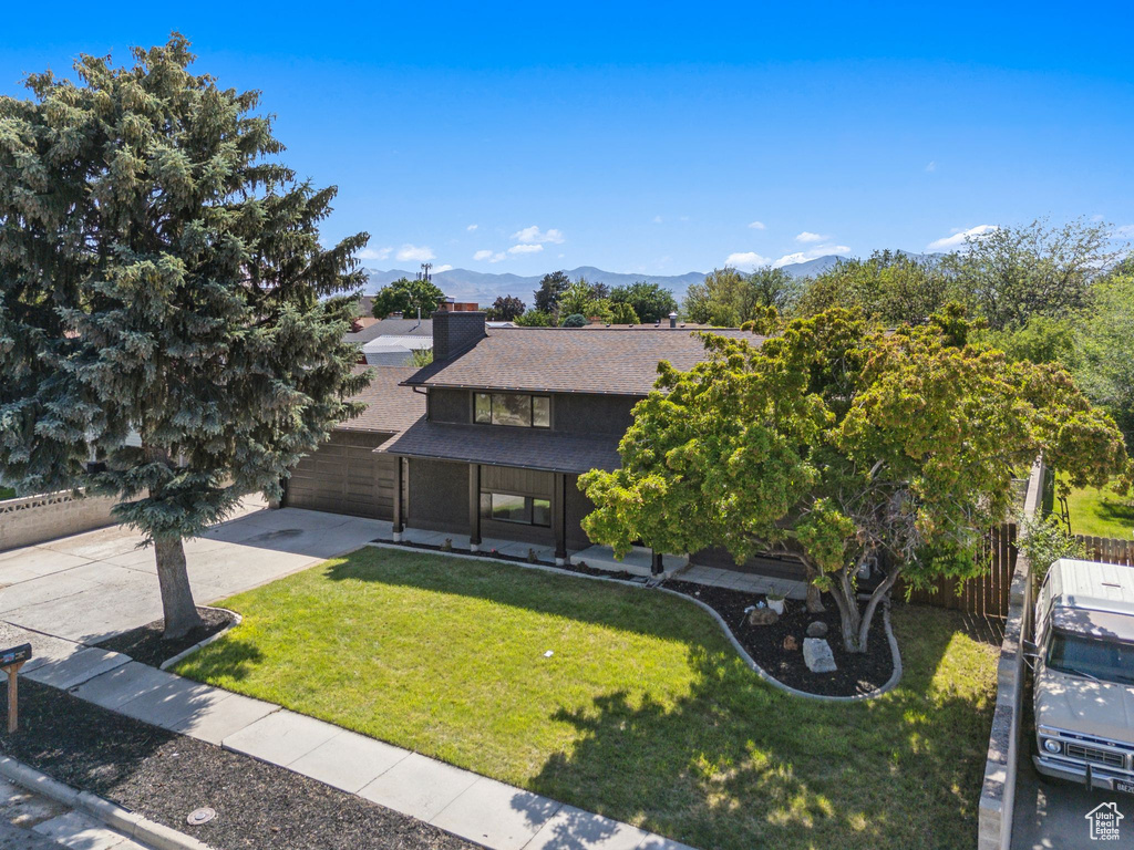 View of front of house featuring a chimney, a shingled roof, driveway, a mountain view, and a garage