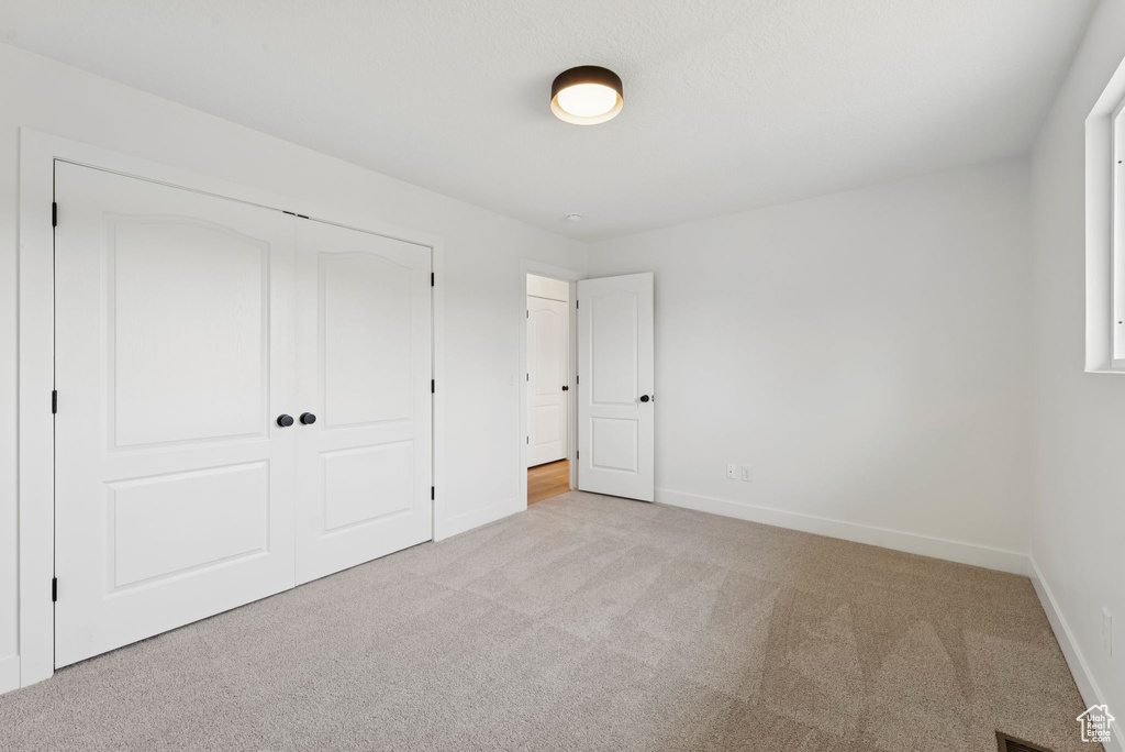 Unfurnished bedroom with carpet flooring, baseboards, and a closet
