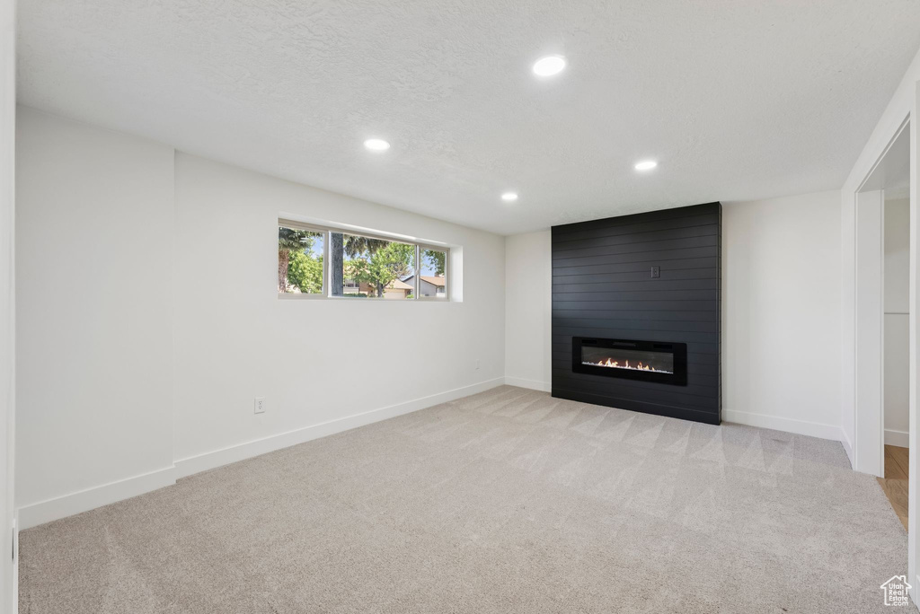 Below grade area featuring a fireplace, recessed lighting, light colored carpet, and baseboards