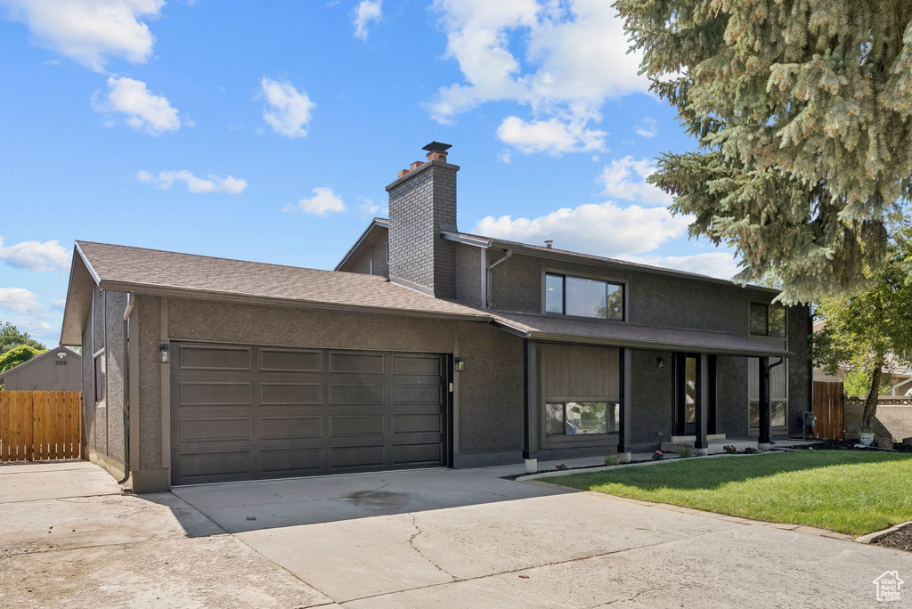 View of front of property with concrete driveway, a chimney, a garage, and stucco siding