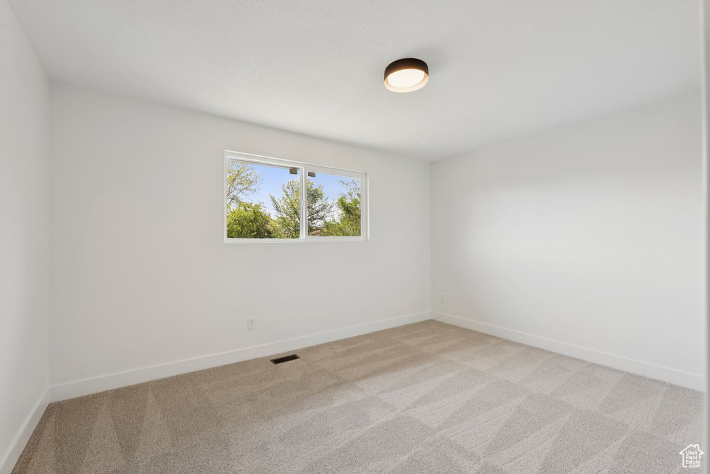 Empty room featuring light carpet and baseboards