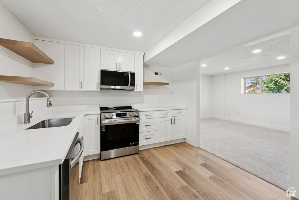 Kitchen with open shelves, stainless steel appliances, a sink, white cabinets, and recessed lighting