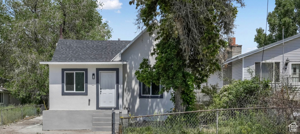 View of front of property featuring stucco siding and roof with shingles
