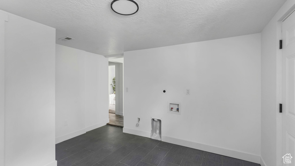 Unfurnished room featuring baseboards, a textured ceiling, and dark wood-type flooring