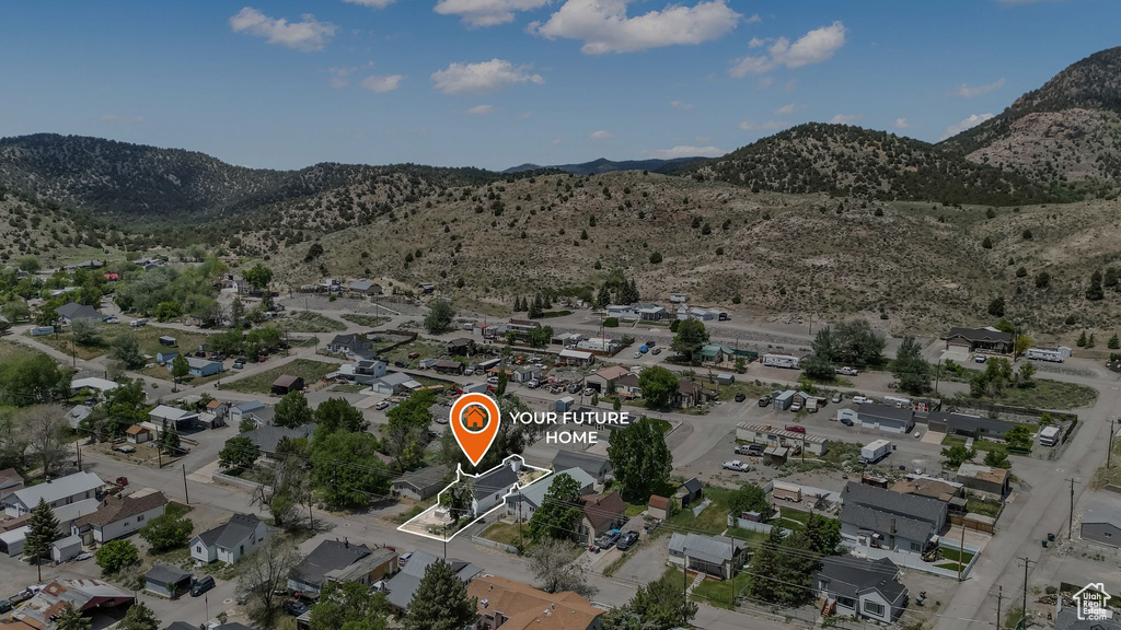 Aerial view of property and surrounding area featuring mountains and nearby suburban area