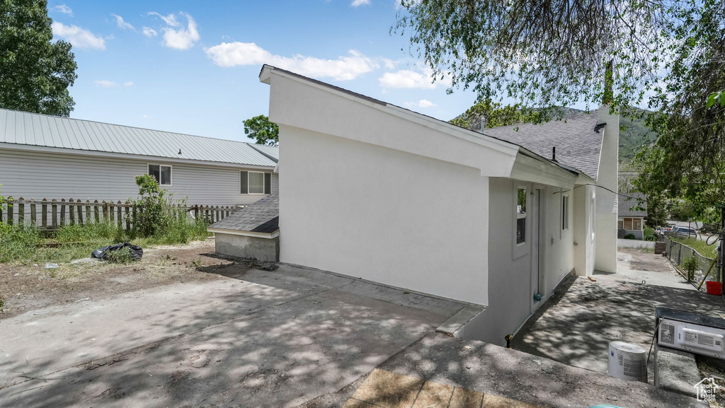 View of home\'s exterior featuring a patio, stucco siding, and a shingled roof