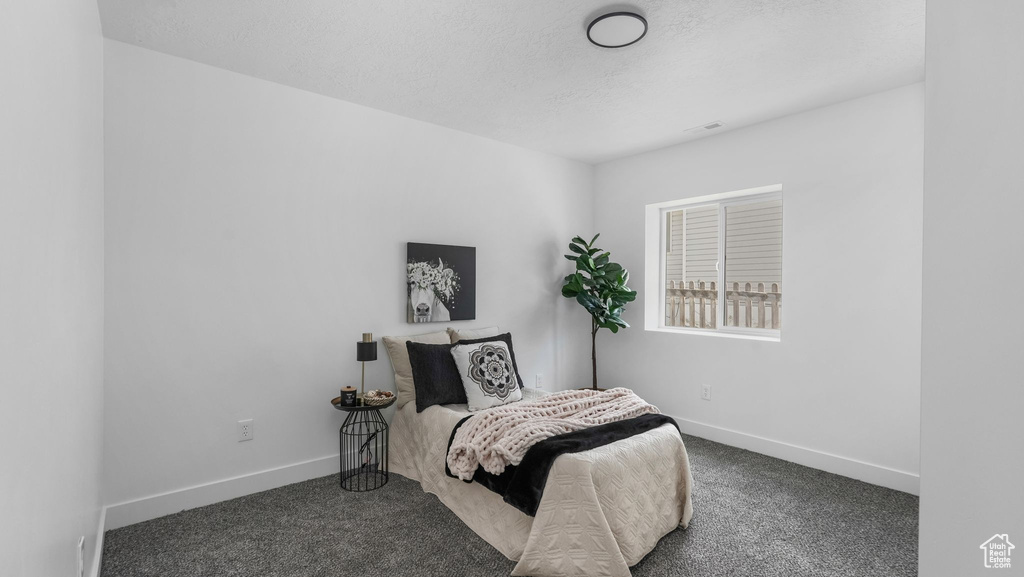 Bedroom featuring carpet, baseboards, and a textured ceiling
