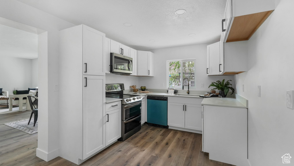 Kitchen featuring appliances with stainless steel finishes, light countertops, dark wood finished floors, white cabinetry, and recessed lighting