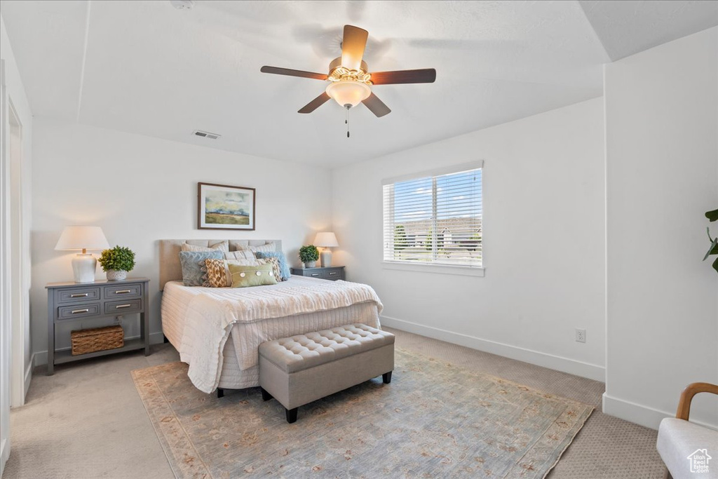 Bedroom featuring light colored carpet, baseboards, and ceiling fan