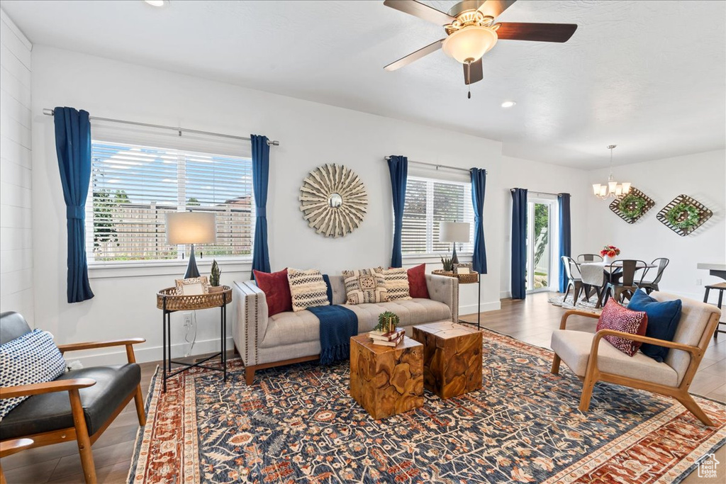 Living area featuring a chandelier, ceiling fan, recessed lighting, baseboards, and wood finished floors