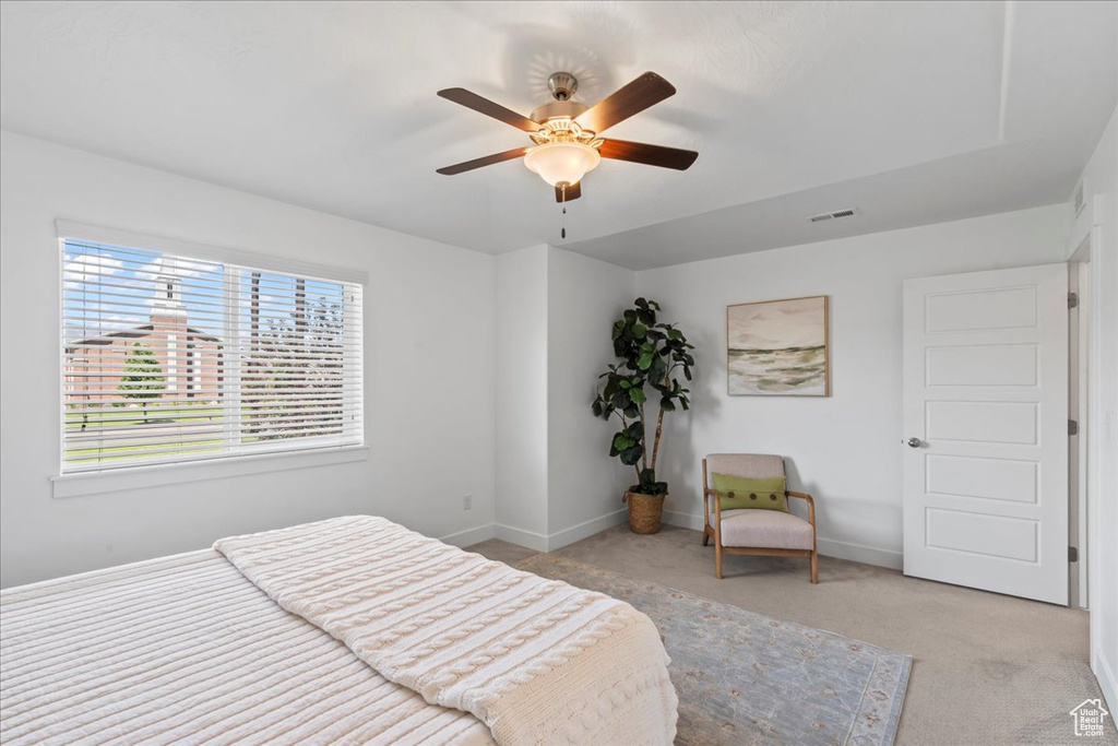Bedroom with light colored carpet, baseboards, and ceiling fan