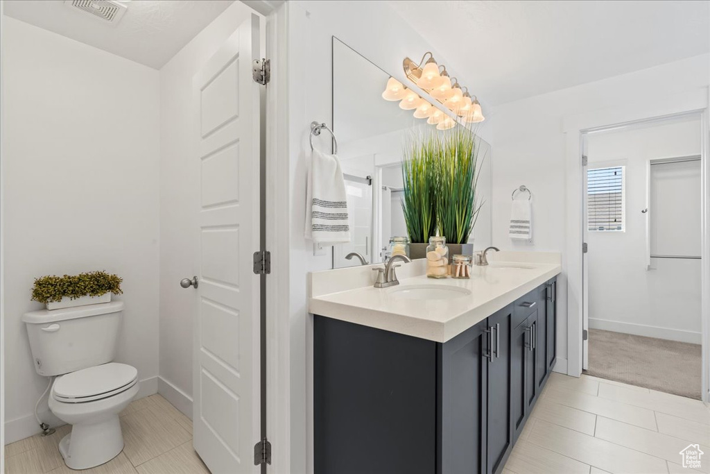 Full bathroom featuring double vanity, tile patterned flooring, toilet, and baseboards