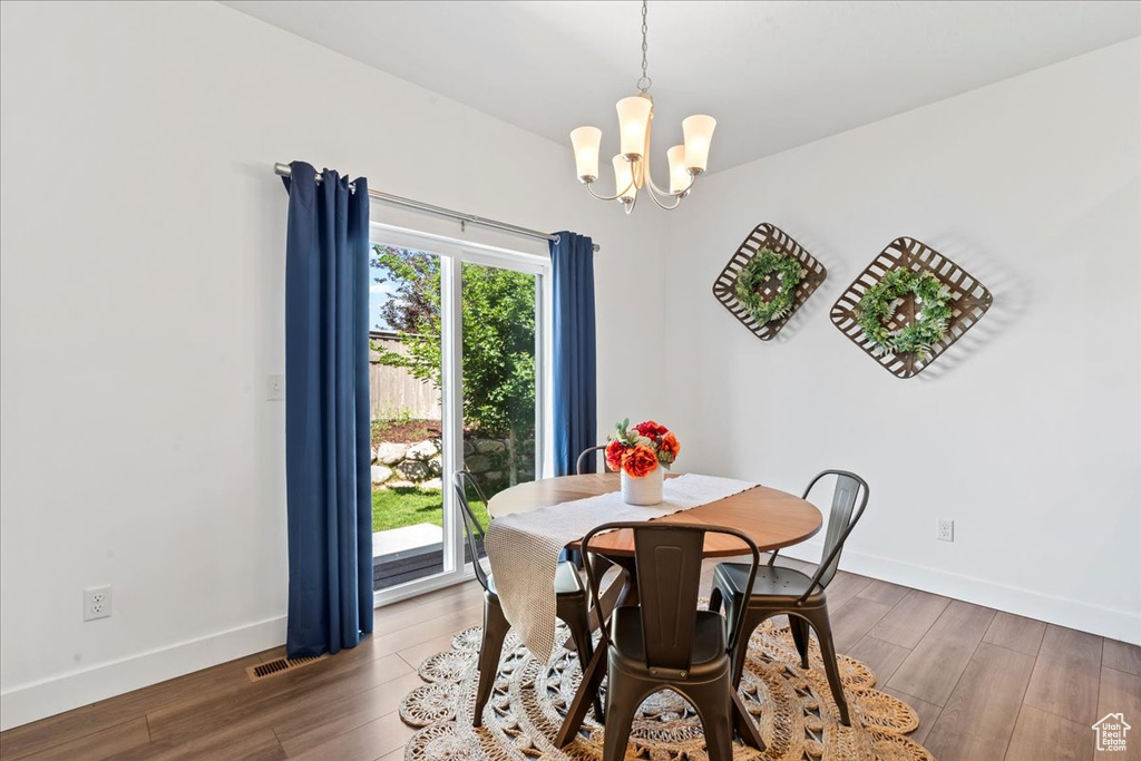 Dining room featuring a chandelier, wood finished floors, and baseboards