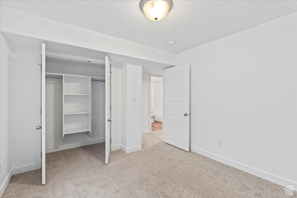 Unfurnished bedroom with carpet floors, baseboards, a textured ceiling, and a closet