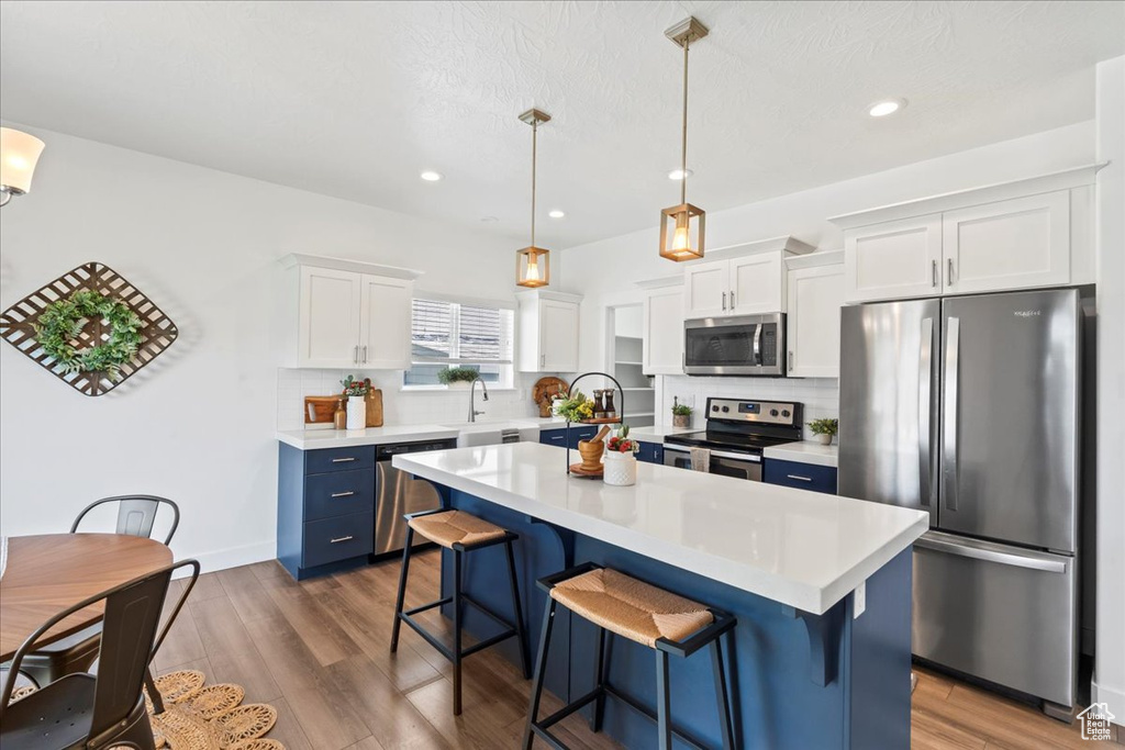 Kitchen featuring stainless steel appliances, light countertops, a breakfast bar area, white cabinetry, and recessed lighting