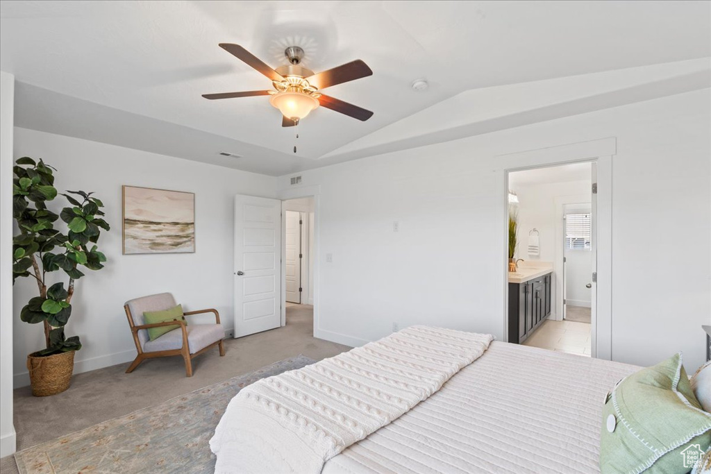 Bedroom featuring vaulted ceiling, light colored carpet, baseboards, ensuite bath, and a ceiling fan